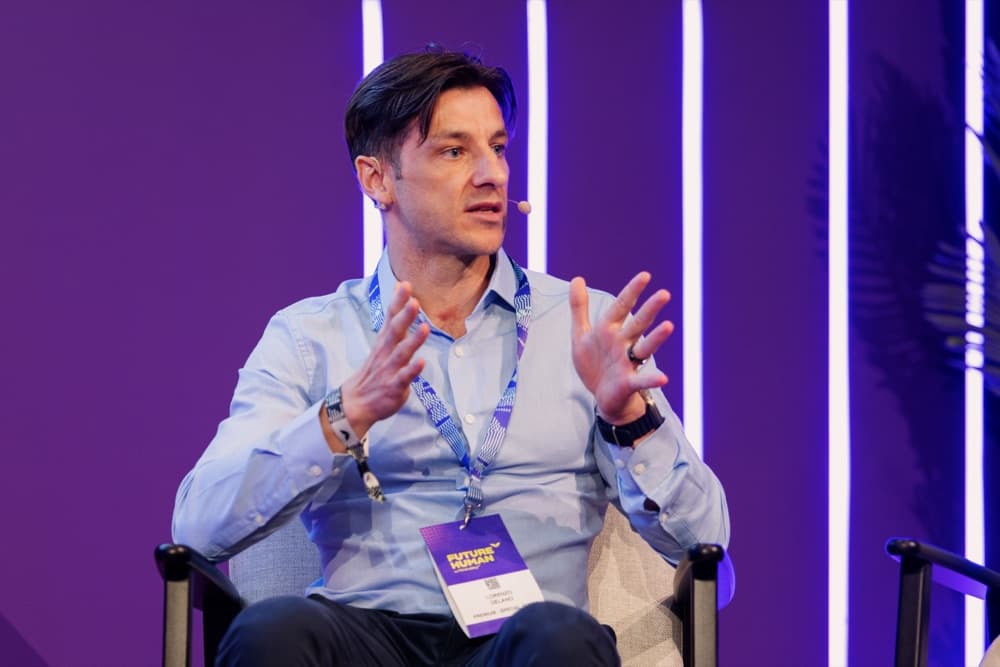 Delano gesturing while speaking on a panel stage in Dubai